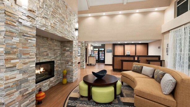 Un vestíbulo moderno con chimenea de piedra, una mesa redonda de madera y un sofá color beige.