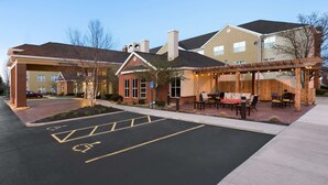 Un hotel con un área de estar al aire libre techada, un estacionamiento con plazas para discapacitados y la entrada al edificio.