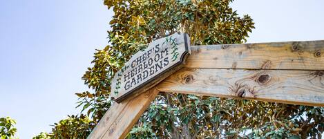 Un letrero de madera con la inscripción 'CHEF'S HOME GARDEN' sobre un fondo de árboles.