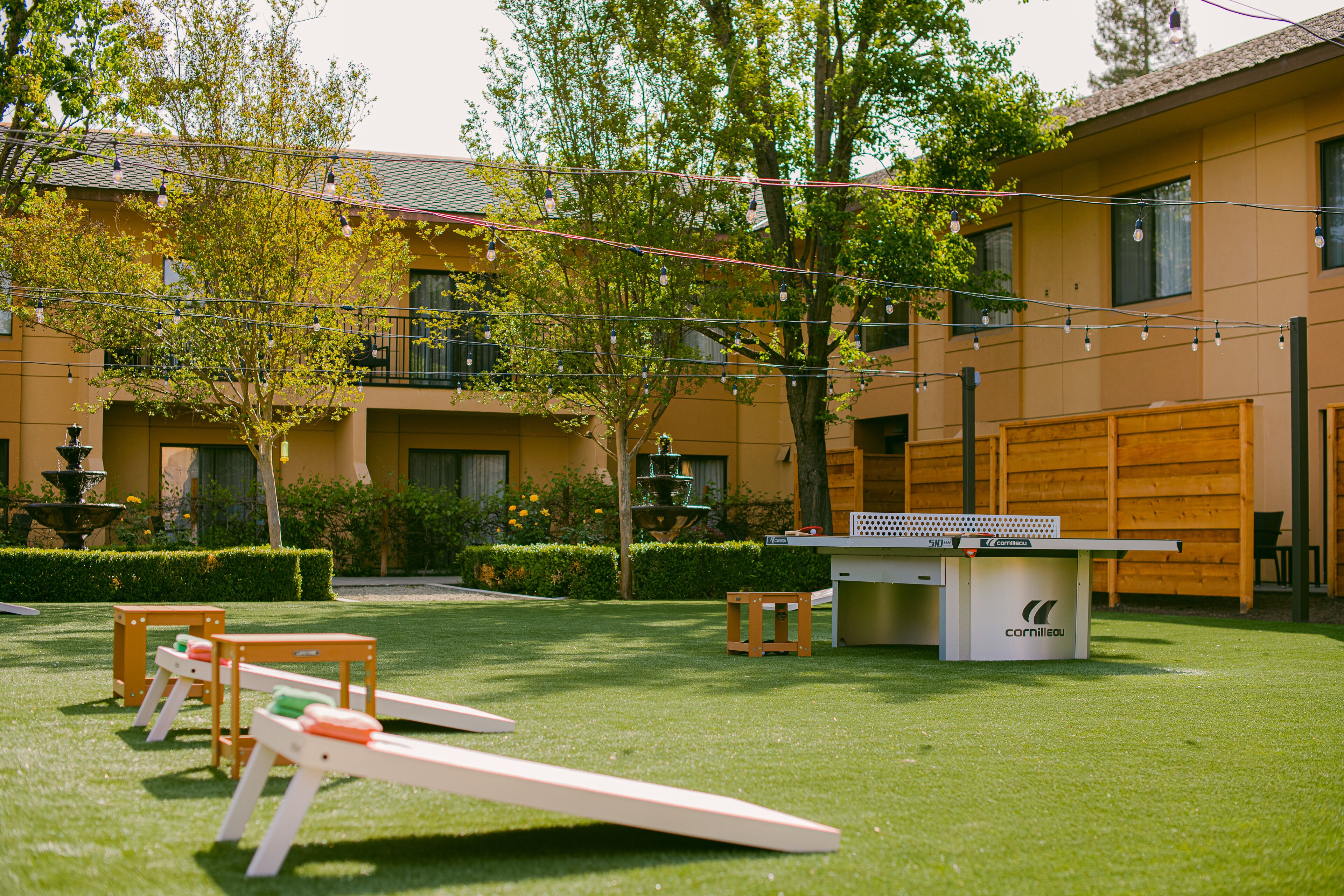 A courtyard with a ping pong table, outdoor seating, and a fountain.