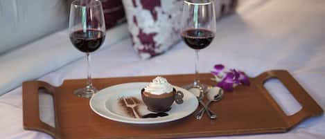 Una bandeja con un cupcake de chocolate y dos copas de vino tinto sobre una mesita.