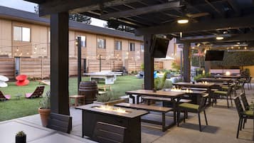 Relax in comfort with ample seating and a fire feature, surrounded by lush greenery and a pergola.