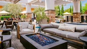 An outdoor patio area with seating arrangements, a fire pit, and stone pillars. - Napa Valley Marriott Hotel & Spa (Napa)