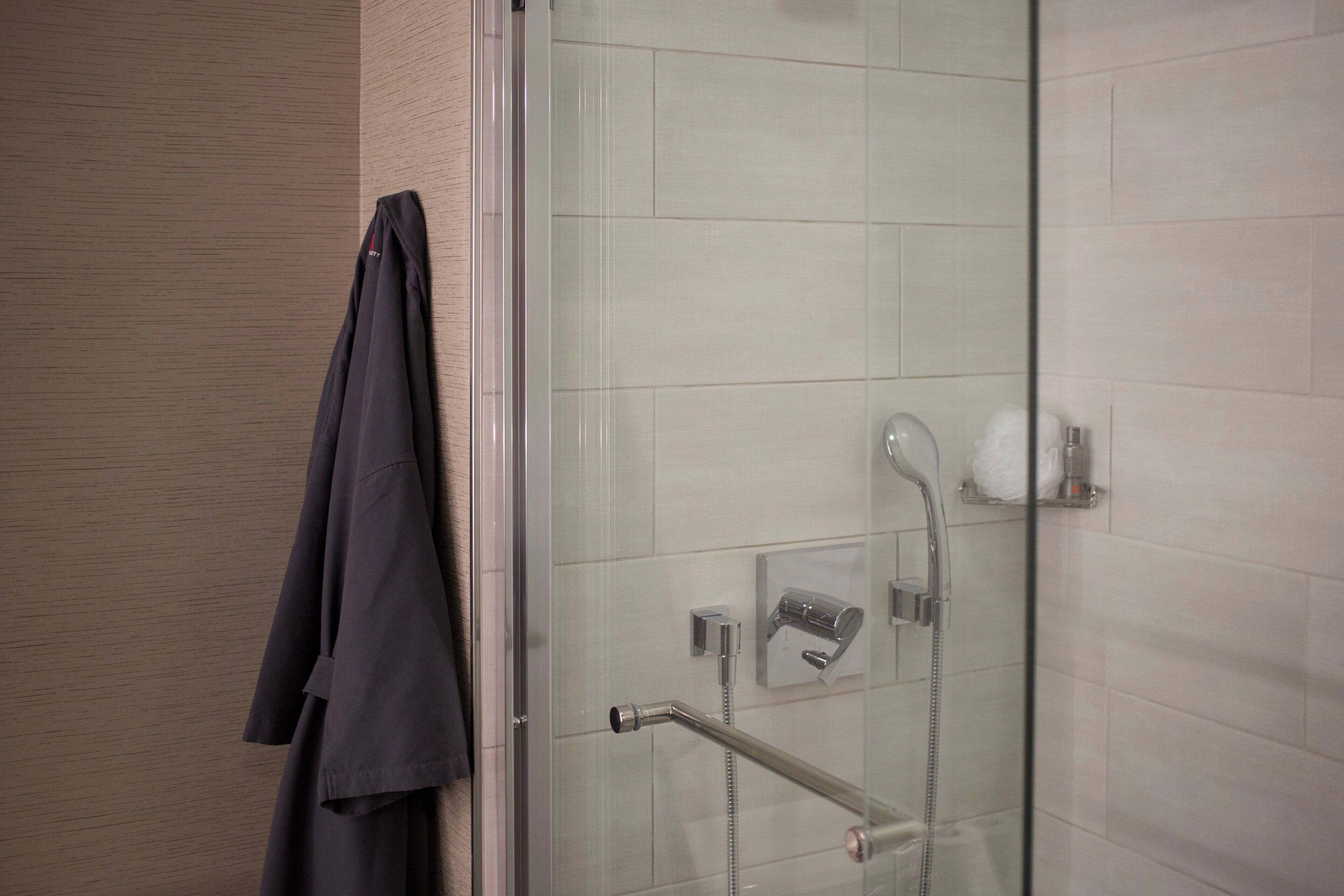 A modern bathroom with a glass shower enclosure, a towel rack, and a toilet paper holder.