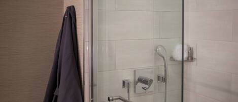 A modern bathroom with a glass shower enclosure, a towel rack, and a toilet paper holder.