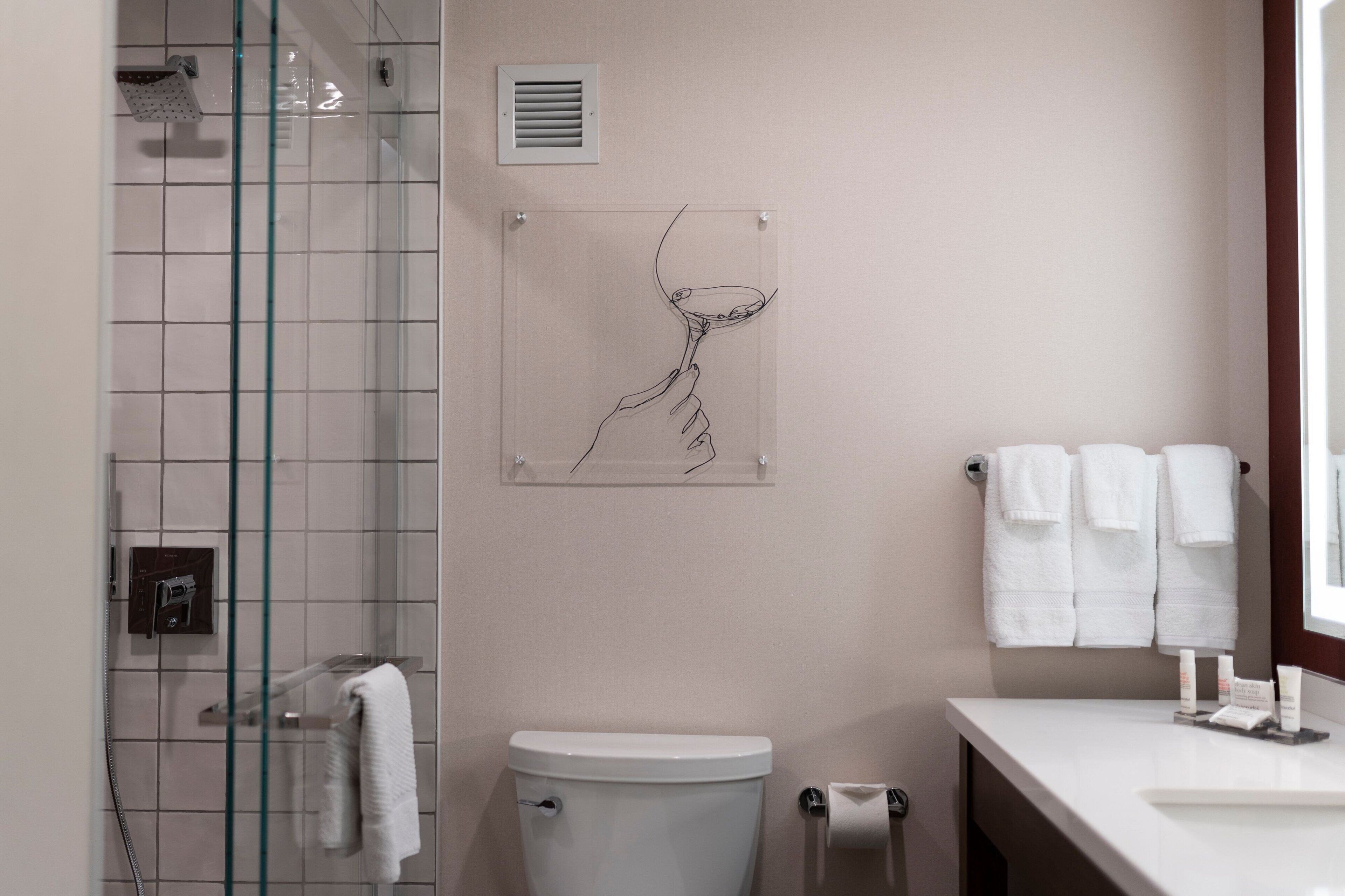 Un baño moderno con cabina de ducha de vidrio, inodoro y lavabo con toallas.