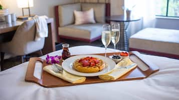 Ein Frühstücksarrangement mit einem Waffel, Erdbeeren, Blaubeeren und Champagnergläsern auf einem Tablett.