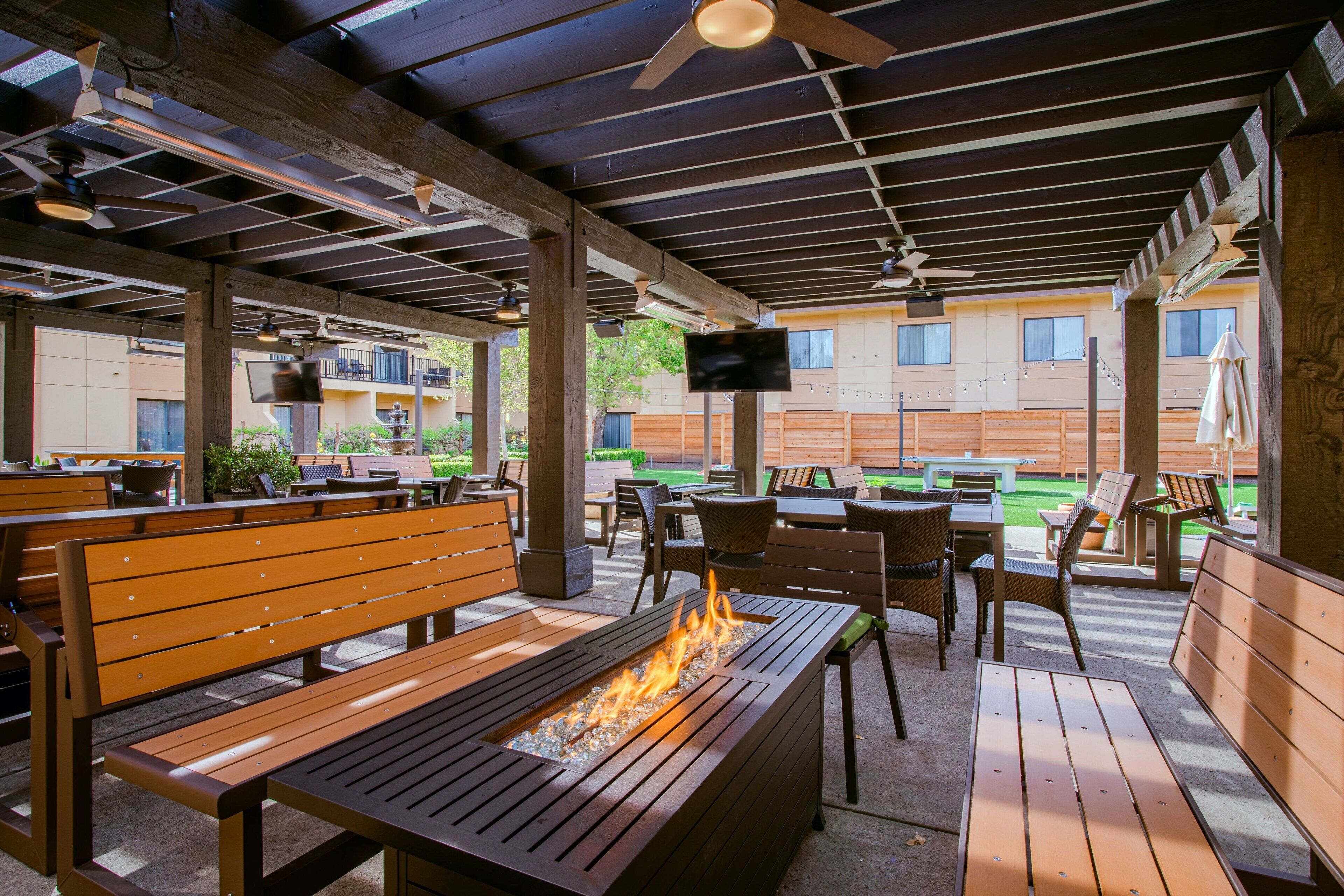 Un patio al aire libre con bancos, mesas y una chimenea.