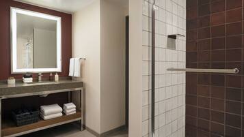 A modern bathroom with a large mirror, a sink, and a shower area.