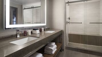 A modern bathroom with two sinks, a large mirror, and a glass-enclosed shower.