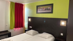 Hotelkamer met een bed, twee nachtkastjes, een hoofdeinde, een raam met gordijnen, en een ingelijste foto aan de muur.