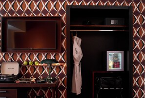 A hotel room with a minibar, a television, a desk with a turntable and records, a coat hanging, and a patterned wall. - Brown Acropol, a Member of Brown Hotels (Athens)