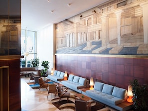 A modern lobby with a seating area, a large wall mural, and a staircase. - Brown Acropol, a Member of Brown Hotels (Athens)