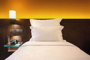 Een hotelkamer met een bed, een bedlampje, een telefoon en een kleine tafel met een glazen blad.