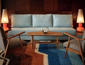 Ein stilvolles Wohnzimmer mit einer Couch, zwei Sesseln, einem Couchtisch und zwei Lampen.