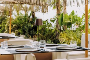 A table set for dining with clear glassware, a lamp, and a view of lush greenery.
