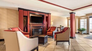 A hotel lobby with a fireplace, comfortable seating, and a television. - Comfort Inn Augusta (Augusta)
