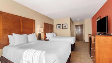 Habitación de hotel con dos camas, televisión, escritorio y armario.