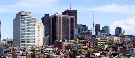 Un paysage urbain mêlant bâtiments modernes et bâtiments historiques, notamment un imposant gratte-ciel en verre et un bâtiment surmonté d’un dôme doré.