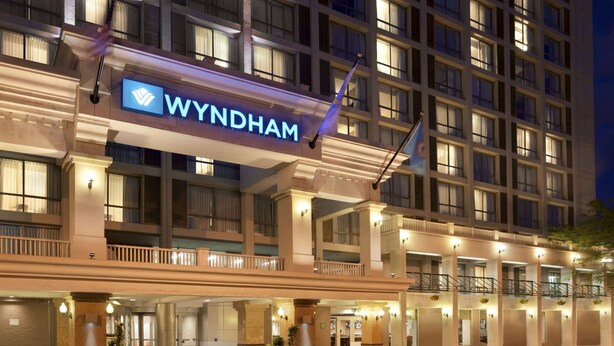 A hotel with a prominent 'WYNDHAM' sign, multiple floors, and a well-lit entrance with potted plants. - Wyndham Boston Beacon Hill (Boston)