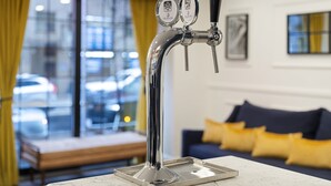A modern tap with two spouts, a marble countertop, a sofa with yellow cushions, and a window with a view of cars. - voco The Franklin New York by IHG (New York)