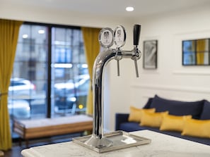 A modern tap with two spouts, a marble countertop, a sofa with yellow cushions, and a window with a view of cars. - voco The Franklin New York by IHG (New York)