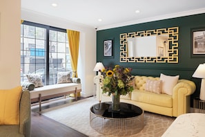 A modern living room with a sofa, a bench, a coffee table with a vase of flowers, and a large window with curtains. - voco The Franklin New York by IHG (New York)