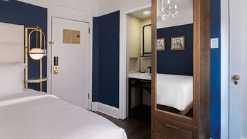 A hotel room with a bed, a mirror, a vanity, and a chandelier.