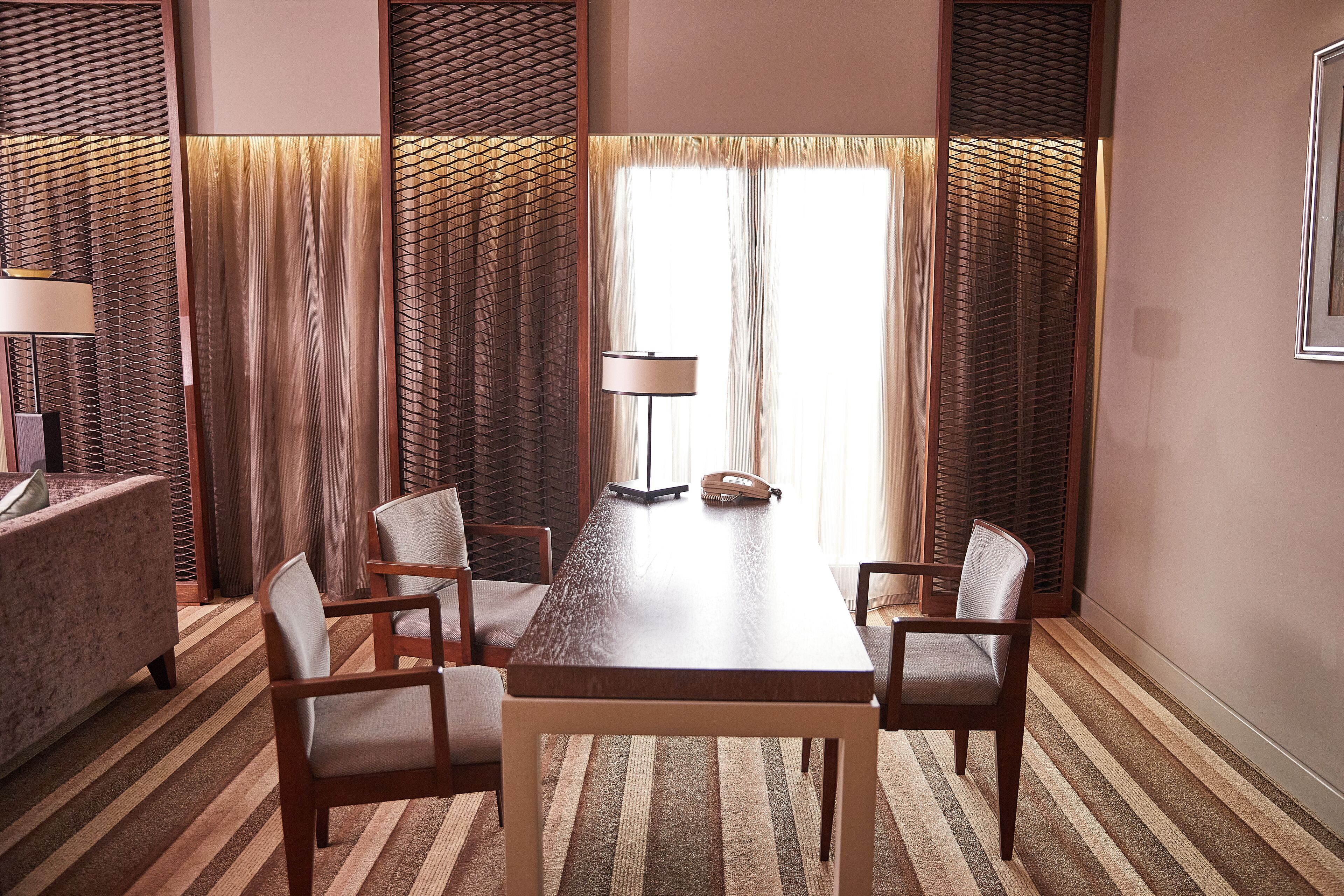 A conference room with a long table, six chairs, a lamp, and a telephone.