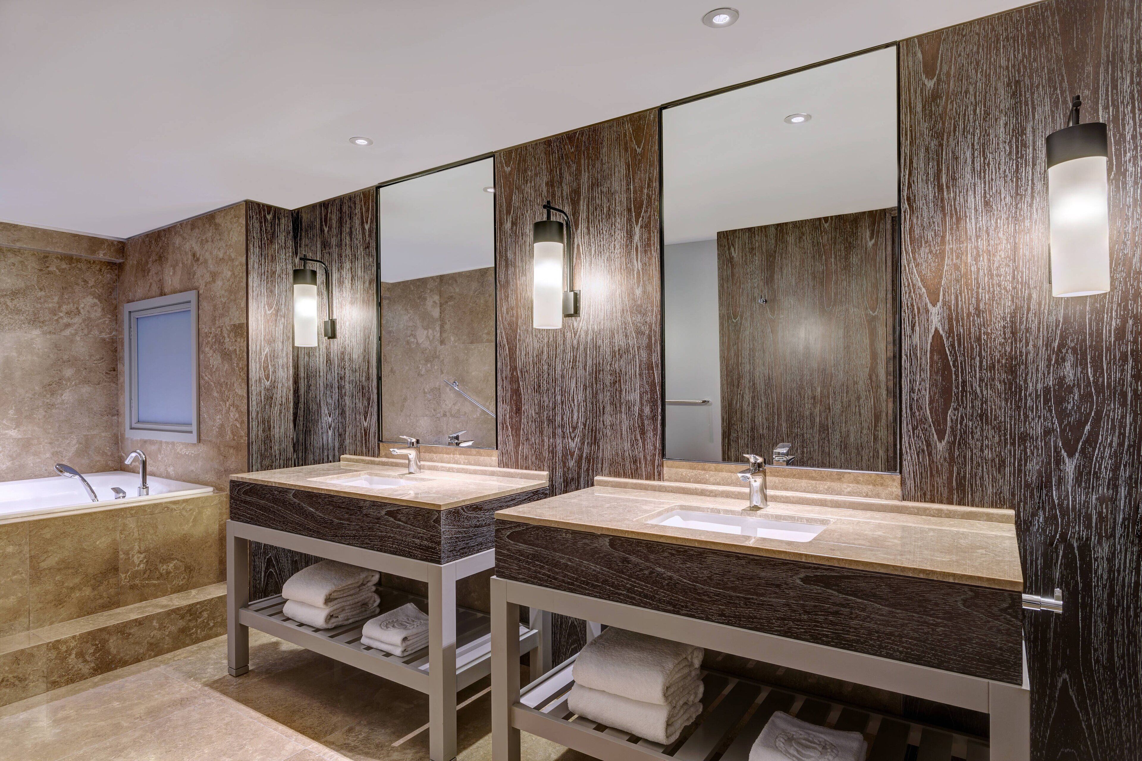 Ein modernes Badezimmer mit zwei Waschbecken, einer Badewanne und einem Spiegel.