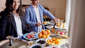 Une table de buffet proposant divers aliments, notamment des fruits, des sandwichs et d’autres collations.