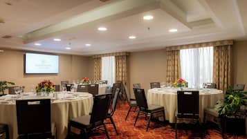 A conference room with multiple tables, chairs, and a projector screen displaying 'SHERATON Lima Historic Center'.