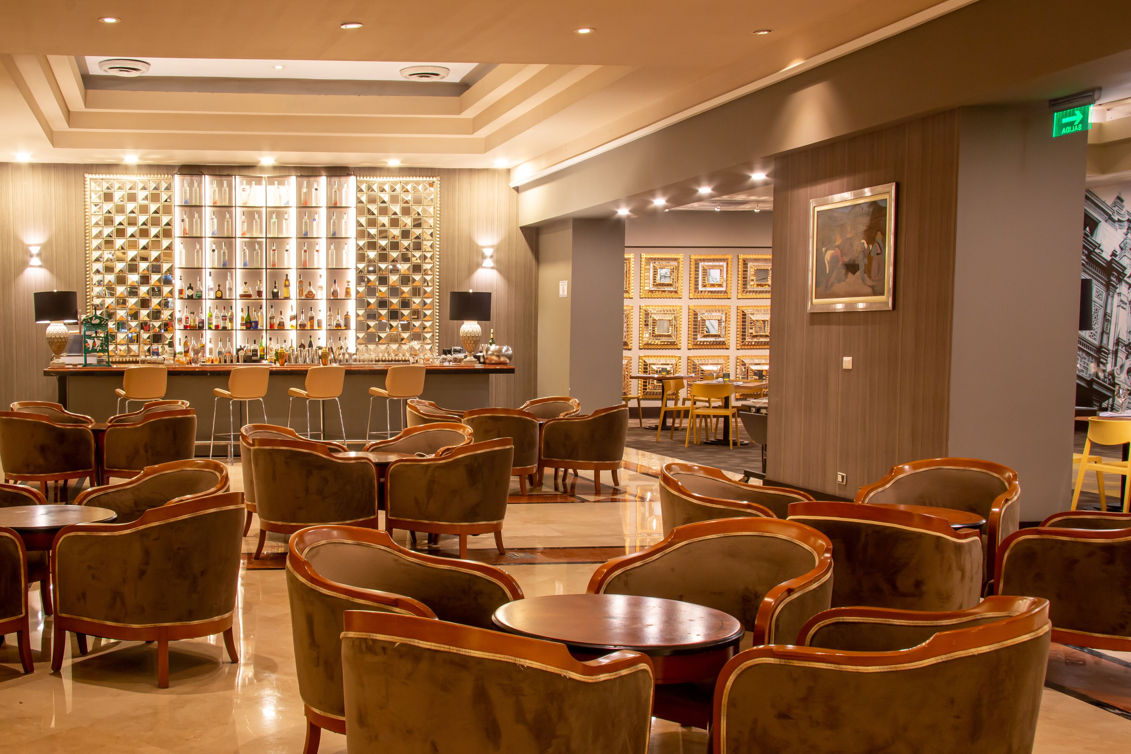 Un hall de hotel con área de bar, disposición de asientos y una pared de fotografías enmarcadas.
