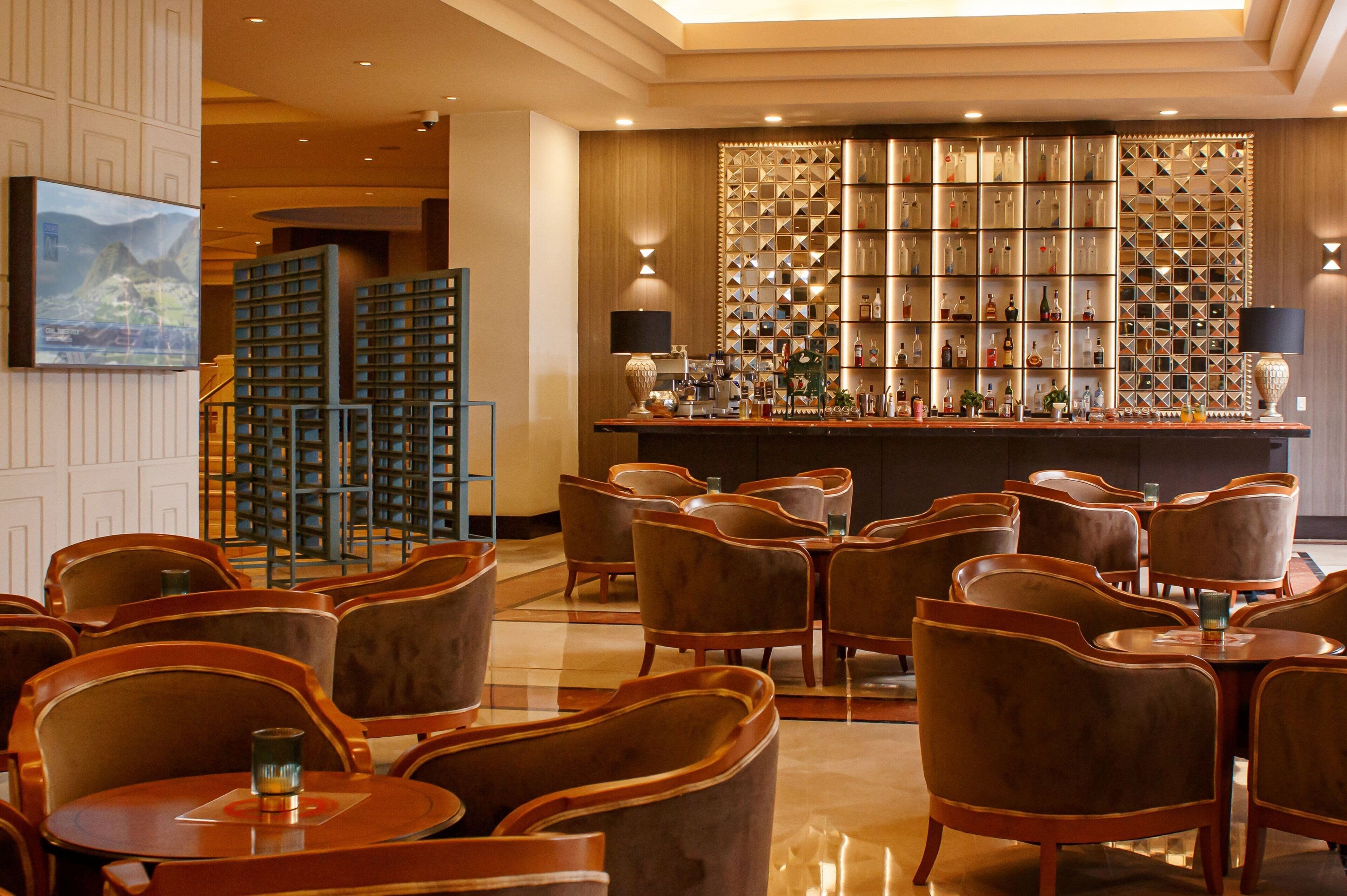 A bar area with a well-stocked shelf of bottles and a seating area with multiple tables and chairs.