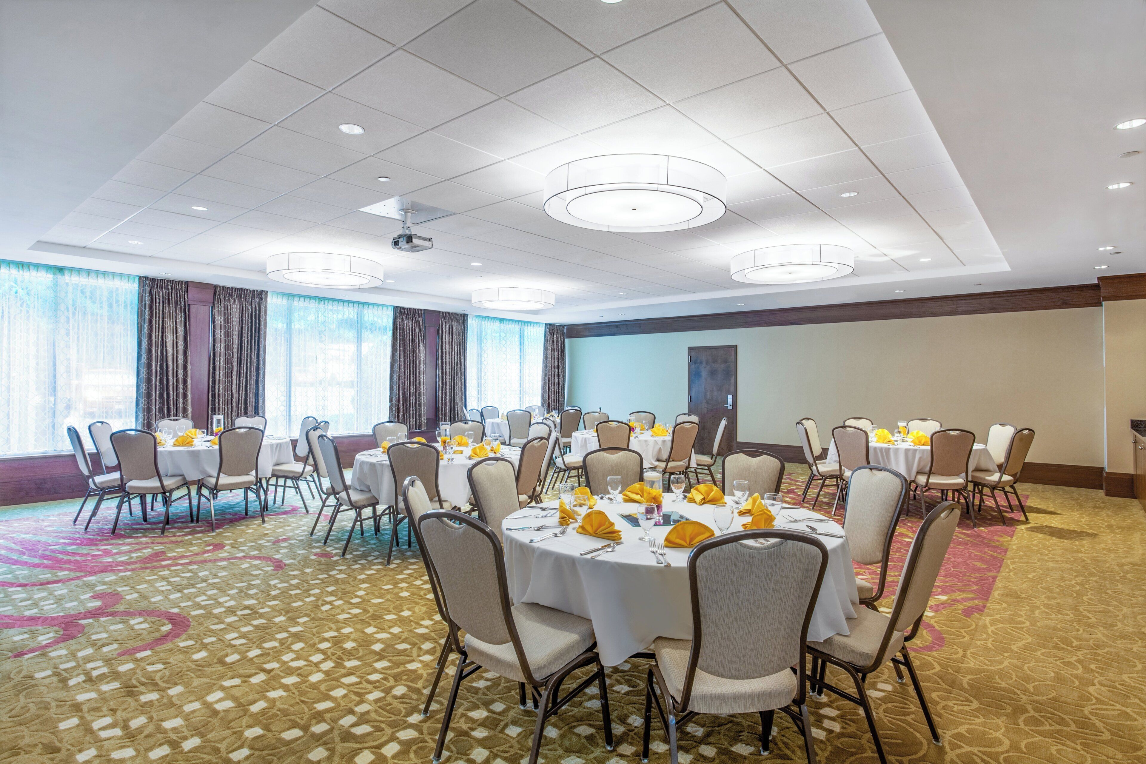 A conference room with round tables, chairs, and a carpeted floor.