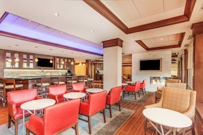 A hotel lobby with a bar area, seating arrangements, and a flat-screen TV mounted on the wall. - Holiday Inn Charlottesville-Monticello by IHG (Charlottesville)