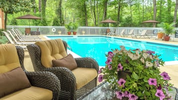 A pool area with lounge chairs, a pool, and potted plants.