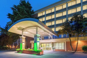 Un hotel con vestíbulo cubierto, ventanas amplias y fachada de ladrillo.