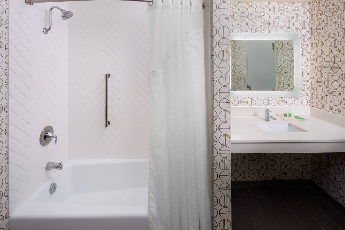 A bathroom with a shower, a sink, and a mirror.