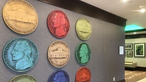 A wall displaying a collection of coins with inscriptions and architectural designs. - Holiday Inn Charlottesville-Monticello by IHG (Charlottesville)
