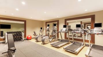 A gym with treadmills, elliptical machines, and free weights.