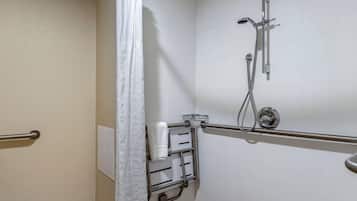 Een badkamer met een douche, handgrepen, een handdoekhouder en een wit gordijn.