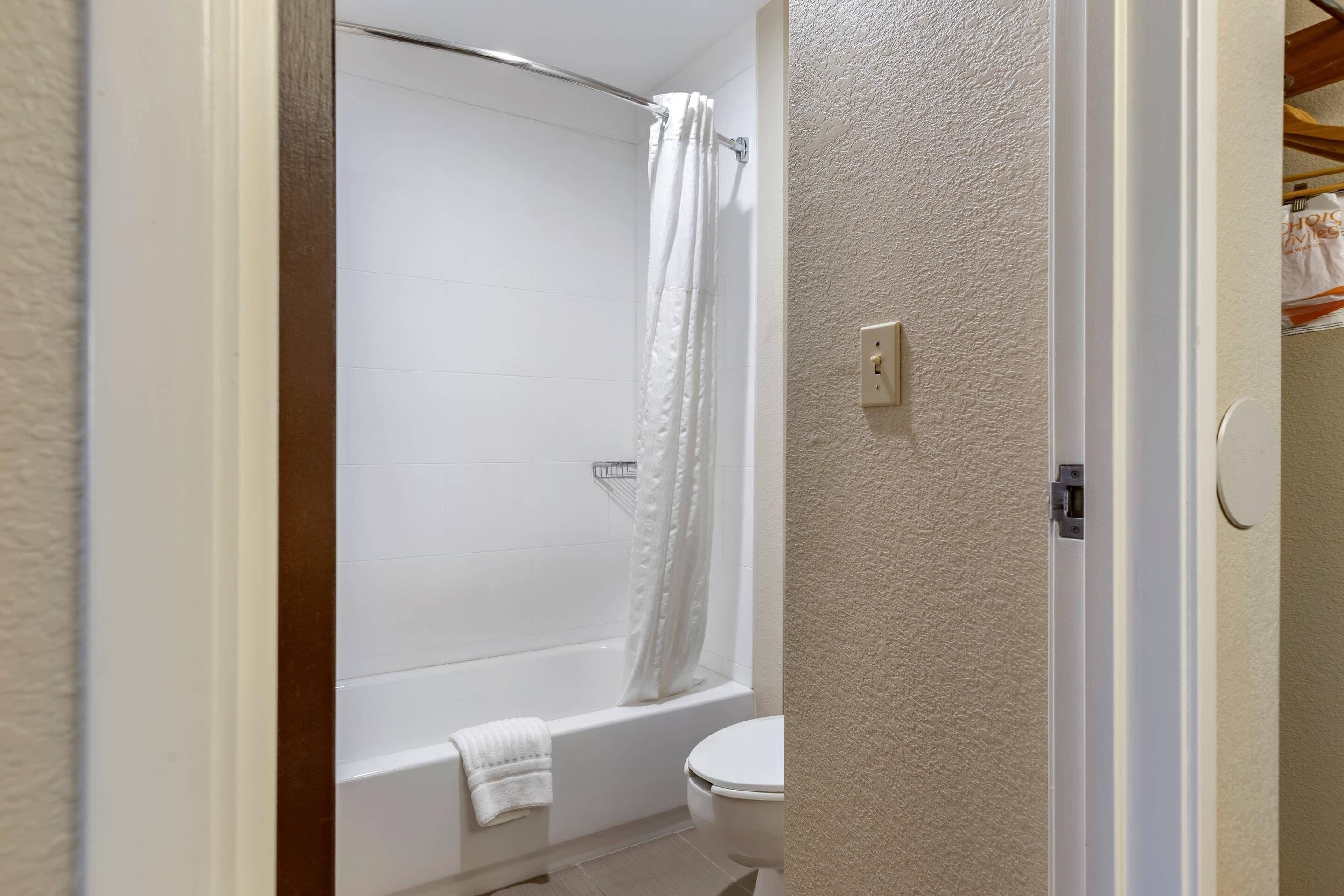 A bathroom with a bathtub, toilet, and shower curtain.