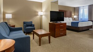 A hotel room with a bed, a TV, a desk, two chairs, and a lamp. - Comfort Inn Near Greenfield Village (Dearborn)