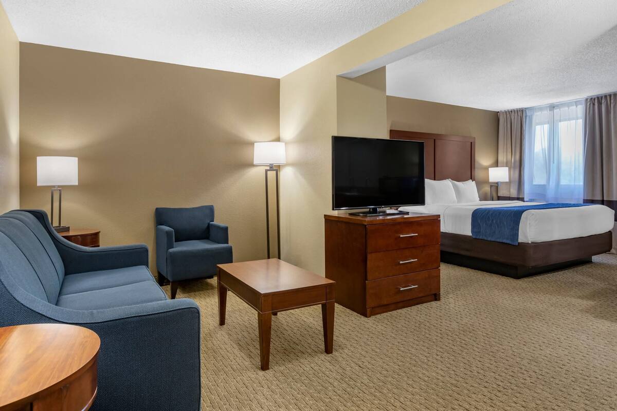 Une chambre d’hôtel comprenant un lit, une télévision, un bureau, deux chaises et une lampe.