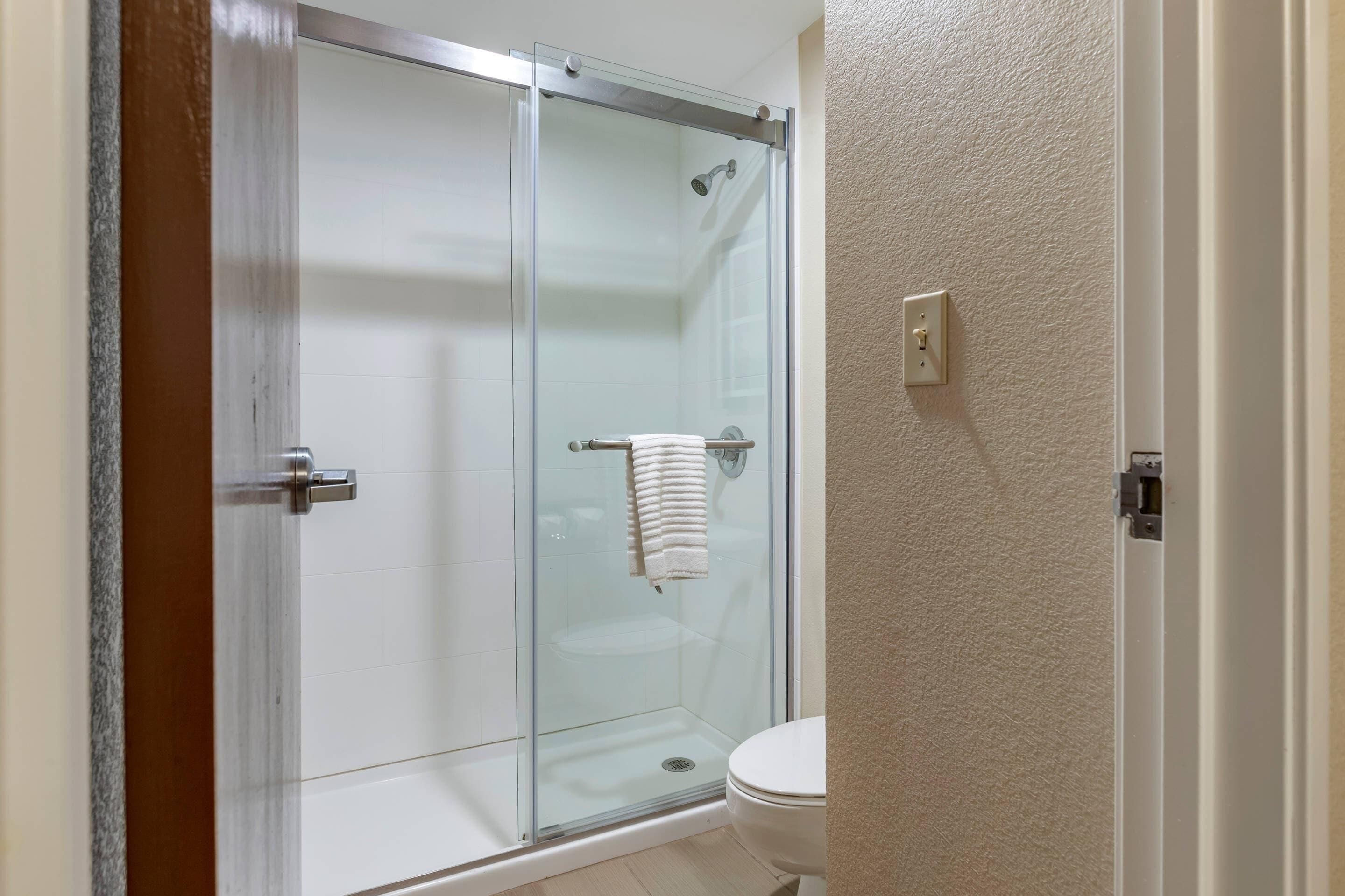 A bathroom with a glass-enclosed shower, a toilet, and a towel rack.