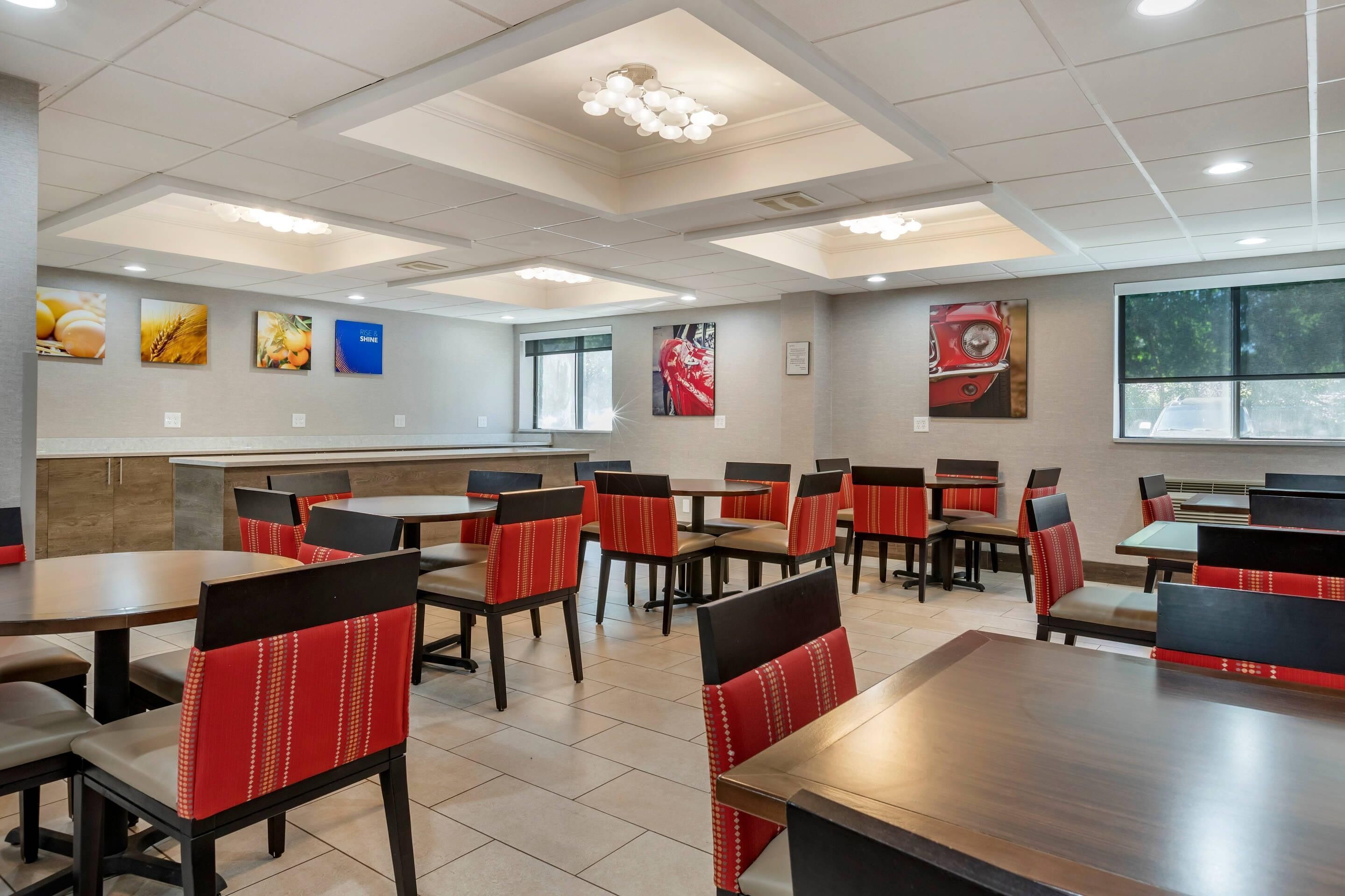 A restaurant with multiple tables and chairs, a ceiling with recessed lighting, and wall art.