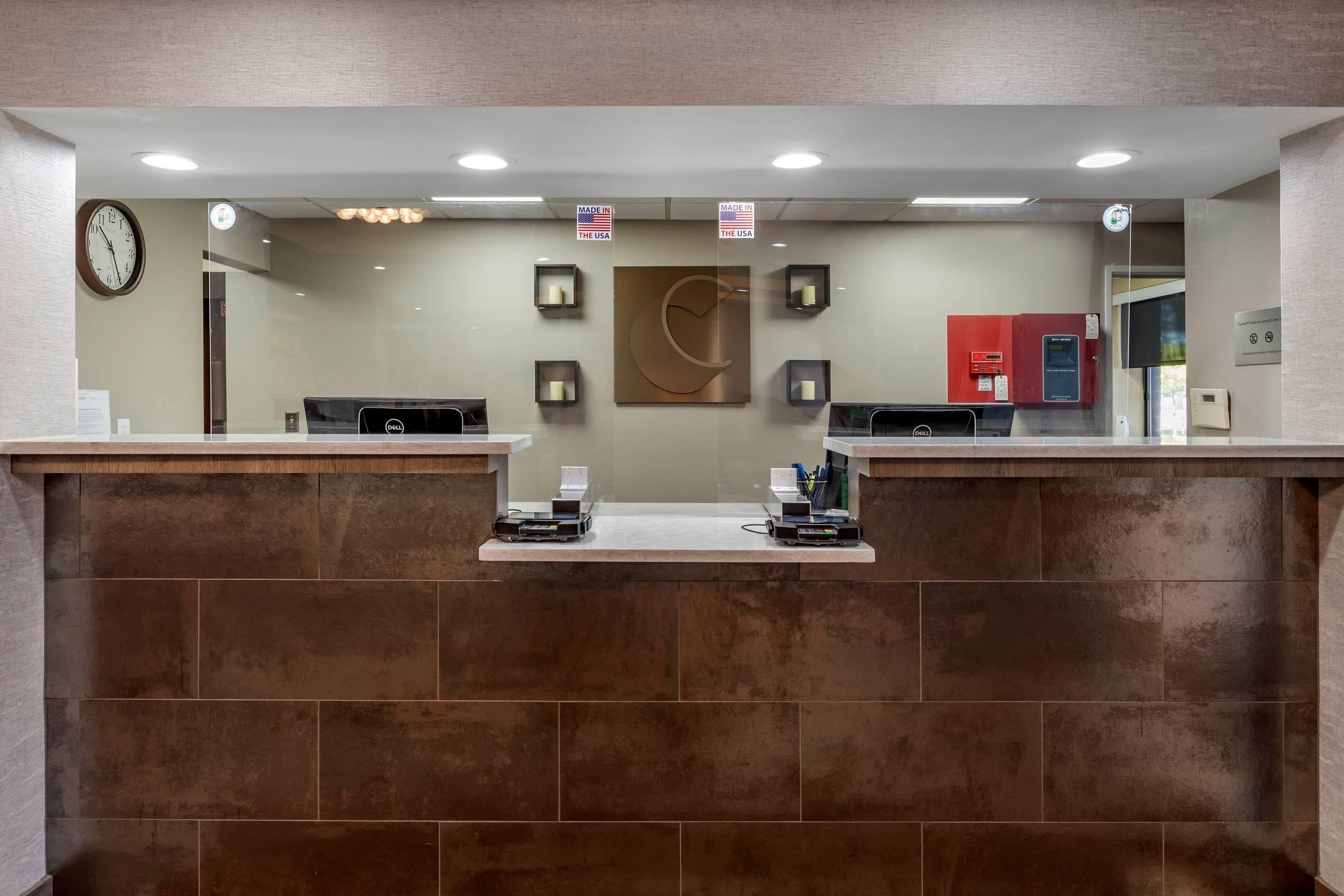 A reception desk with a clock, two computer stations, a red cabinet, and a wall-mounted clock.