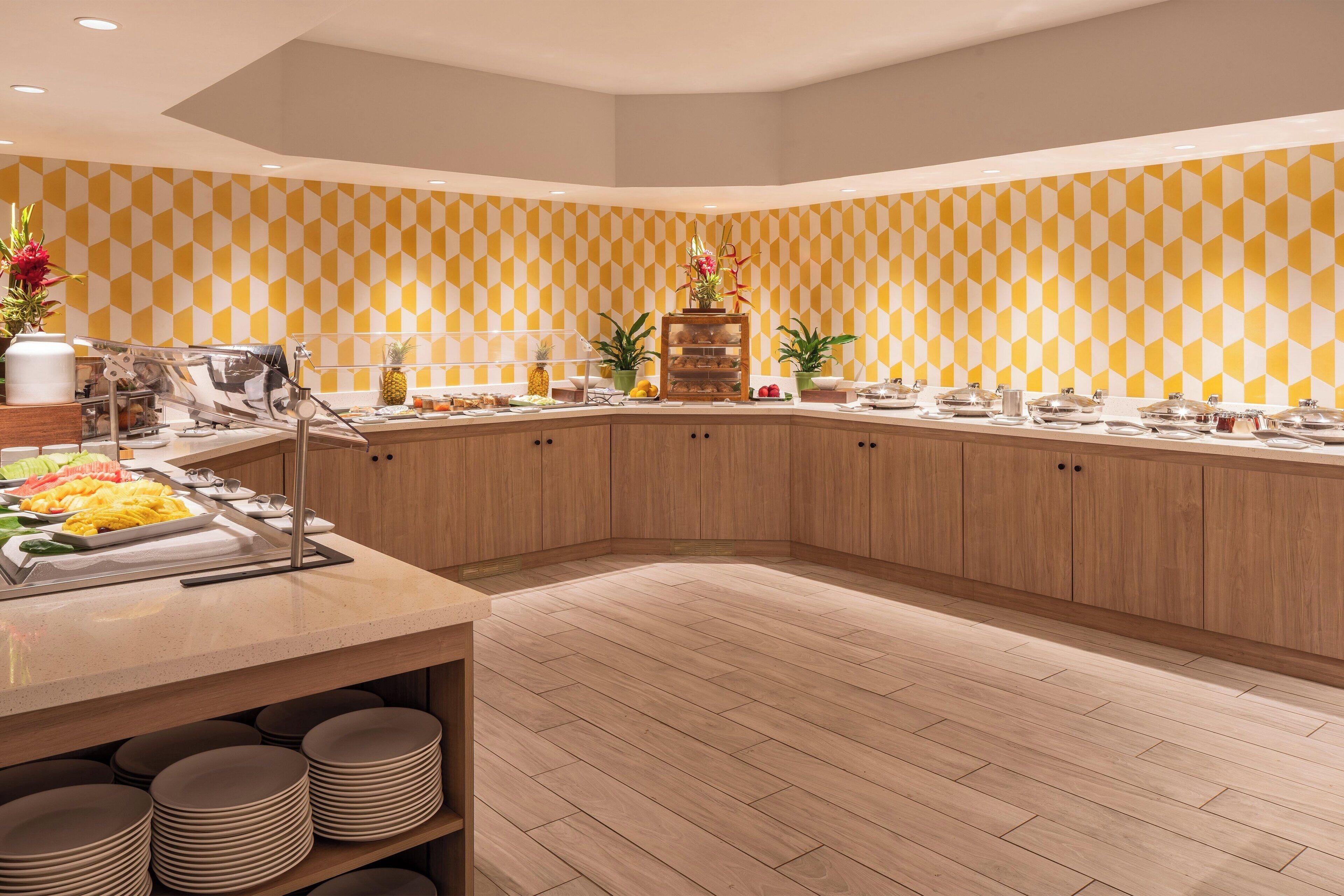 A buffet setup with a variety of food items, wooden cabinets, and a patterned wall.
