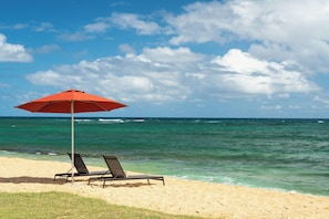 Aan het strand, ligstoelen aan het strand, parasols, yoga op het strand